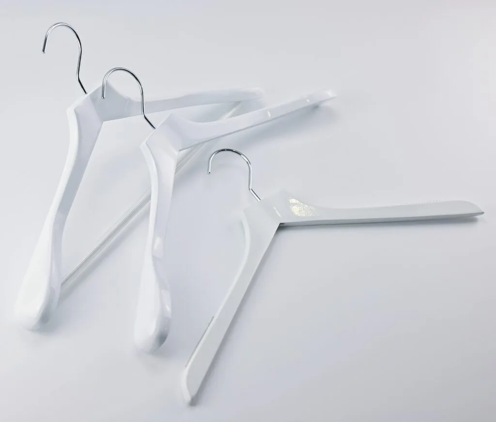 White clothes hangers with metal hooks, arranged on a light background.