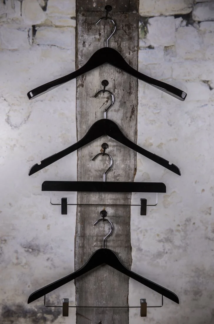 Vier schwarze Kleiderbügel mit mittlerem Clipbügel, vertikal montiert - Passend für komplette Outfits.