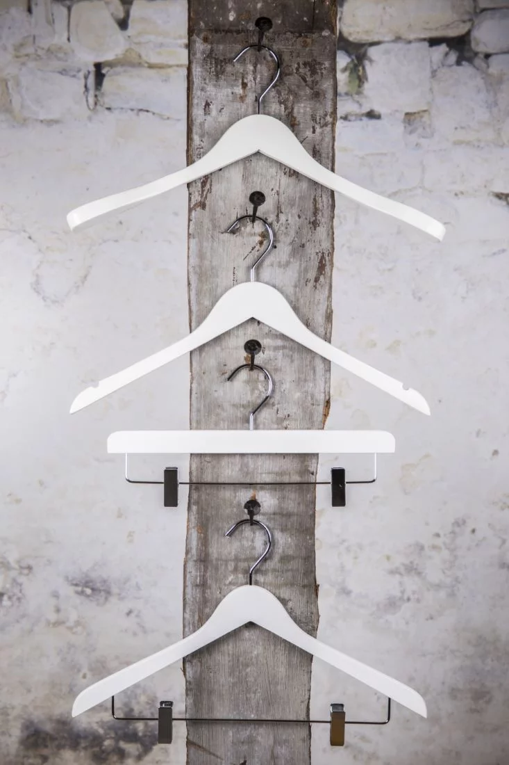 Drei weiße Kleiderbügel mit zentralem Clip-Aufhänger, vertikale Präsentation – Einheitliche Präsentation in Weiß.