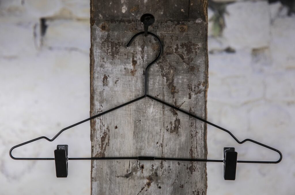 Schwarzer Drahtbügel mit Kverstange und Clip, aufgehäng an Wall – Praktischer Allround-Kleiderbügel.