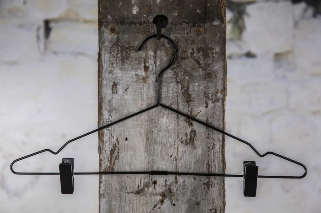 Schwarzer Drahtbügel aus Metall mit Querstange und Clips an der Wand – praktische Allround-Lösung für die professionelle Präsentation von Hosen oder Röcken in Geschäft und Showroom (Clipbügel)