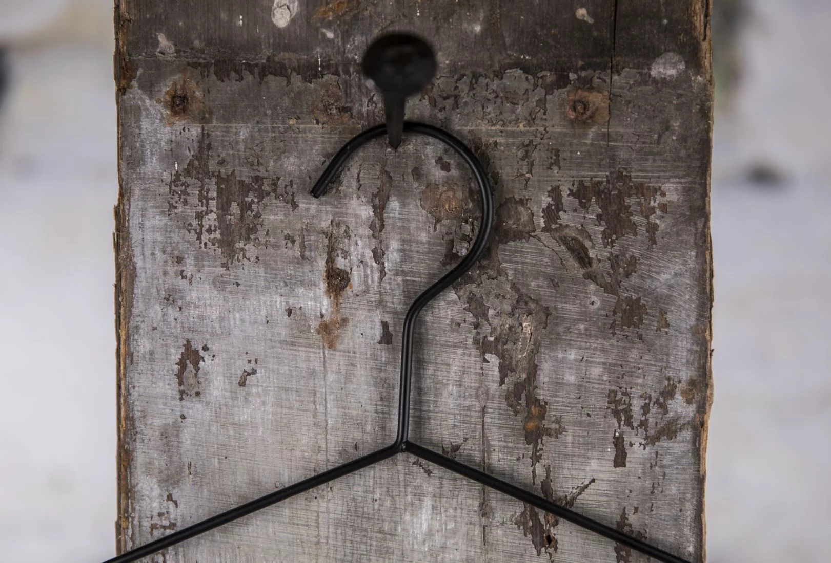 Schlichter schwarzer Drahtbügel mit Haken, aufgehängt an Holzwand – Minimalistisches Design für verschiedene Nutzung.