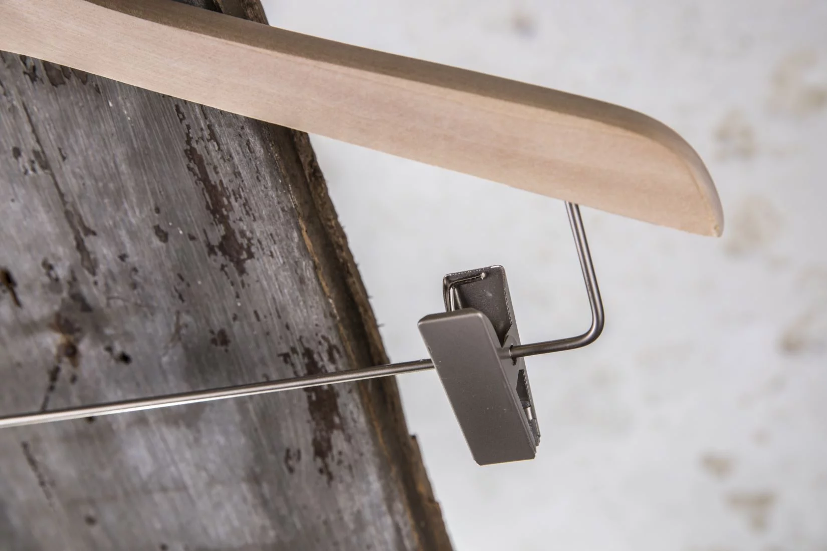 Detailaufnahme eines silbernen Clips an naturfarbenem Hosenbügel – Fokus auf Materialkontrast und Funktion.