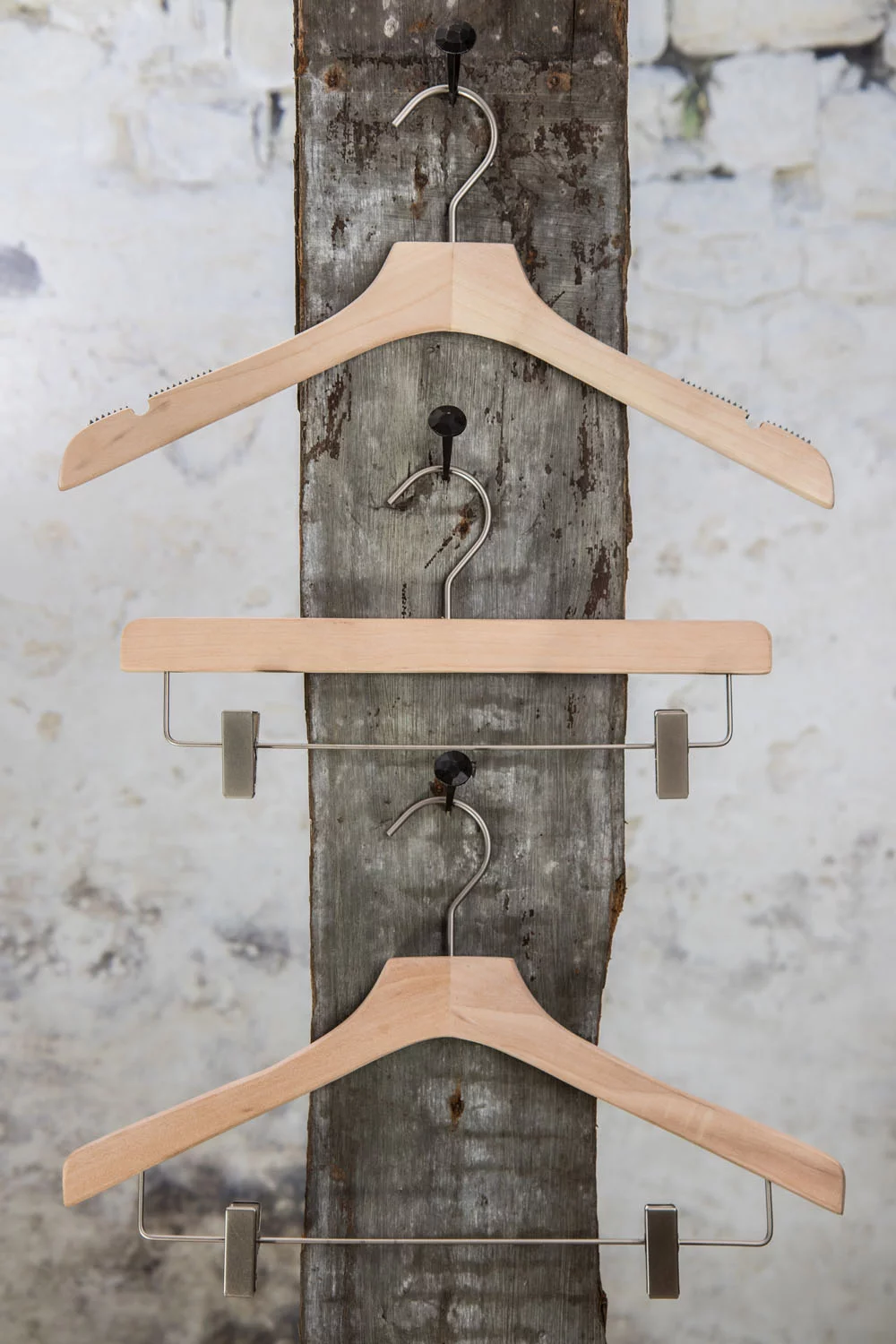 Drei Holzbügel mit Hosenstange und Clips, vertikal präsentt – Kompakte und organizte Lösung für den Einzelhandel.
