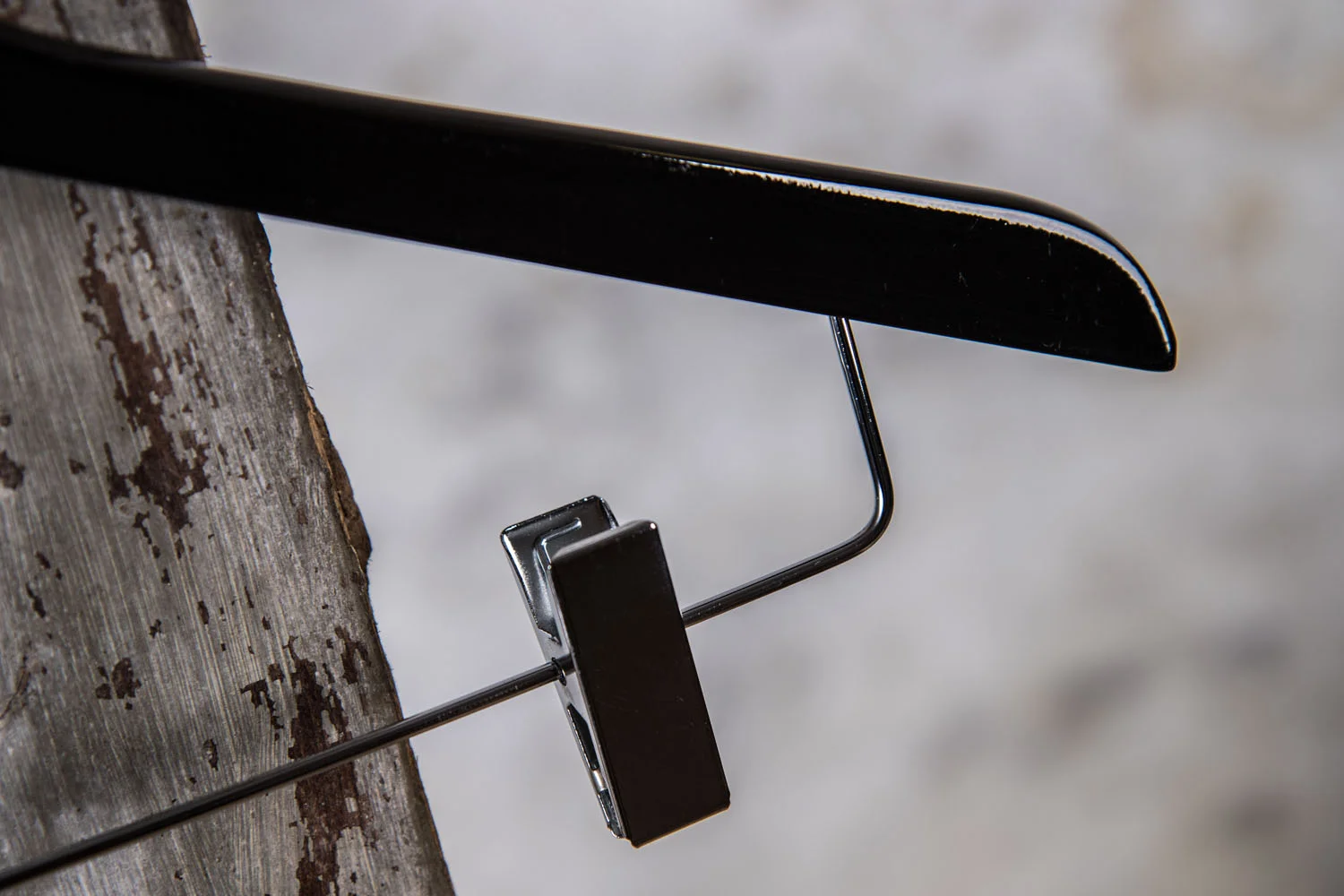 Detailansicht von schwarzem Holzbügel mit Metallclip – robuste und elegante Ausführung.