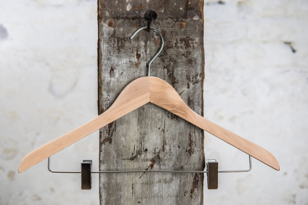 Kleiderbügel aus Naturholz mit schwarzen Clips – klassische Kombination aus Holz und Funktion.