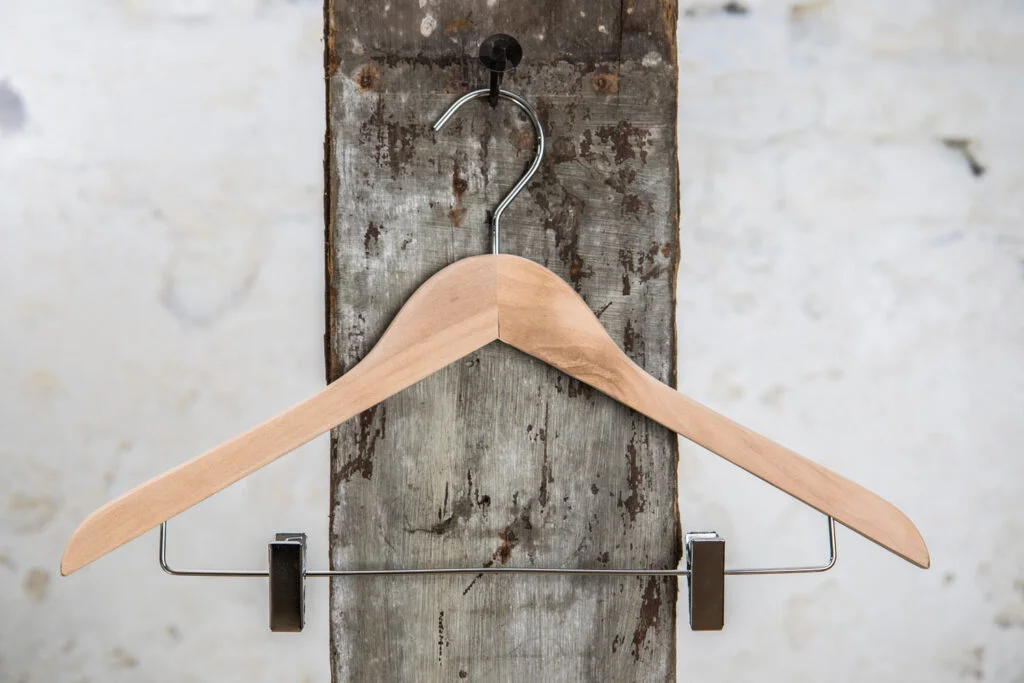 Naturholz-Bügel mit schwarzen Clips – Klassische Kombination von Holz und Funktion.