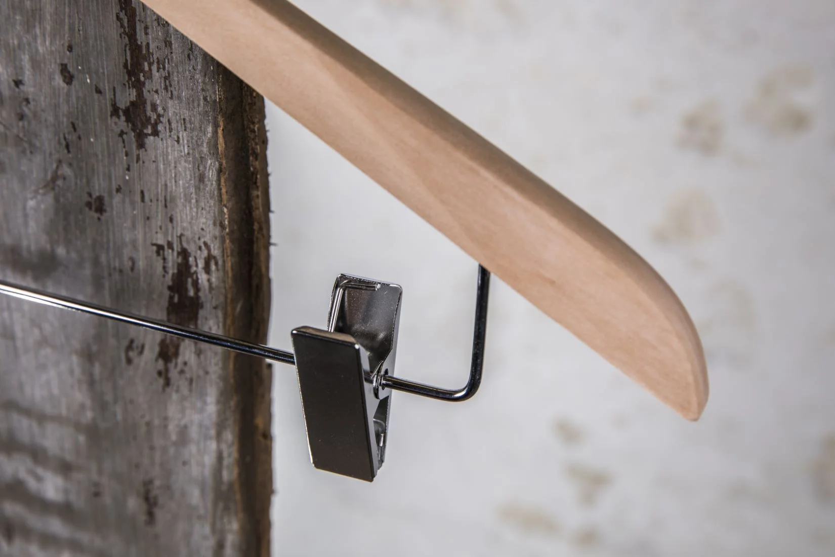 Nahaufnahme eines Holzbügels mit schwarzem Clip – Detailfokus auf Funktion und Material.