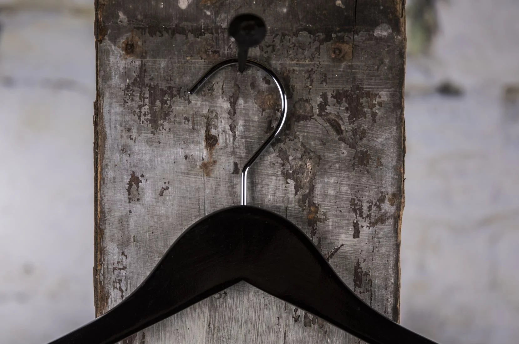 Black coat hanger with wide shoulders hung on the wall - Robust model for professional presentation of heavy clothing in stores and showrooms (coat hanger)