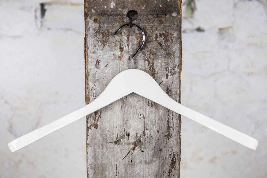 Weißer, Geschwungener Kleiderbügel an Wandhaken – Schlichtes, modernes Design für Kleidung.