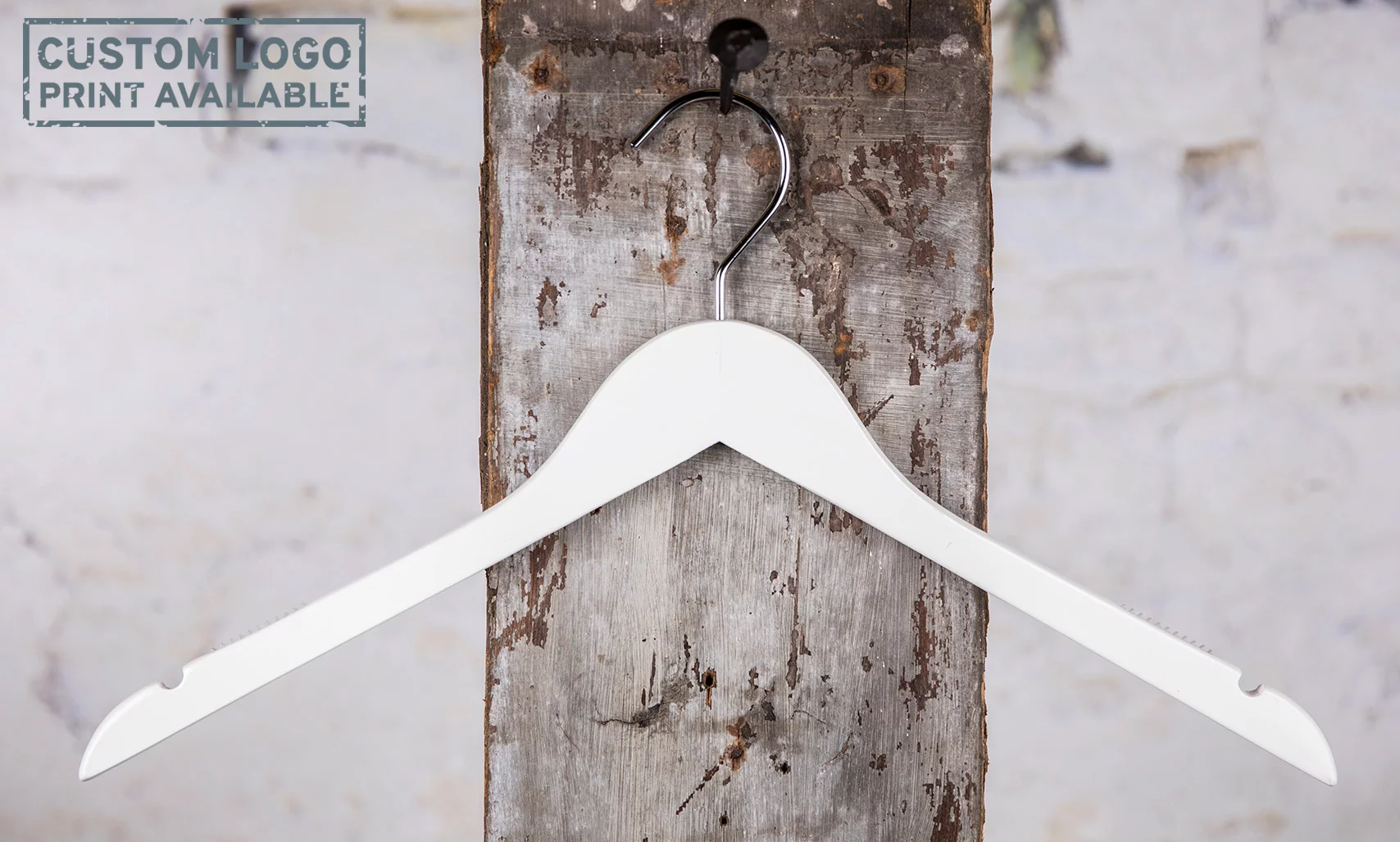 Weißer Kleiderbügel mit geschwungener Form, aufgehangen an einer Wandhalterung – Zeitlos und funktional.