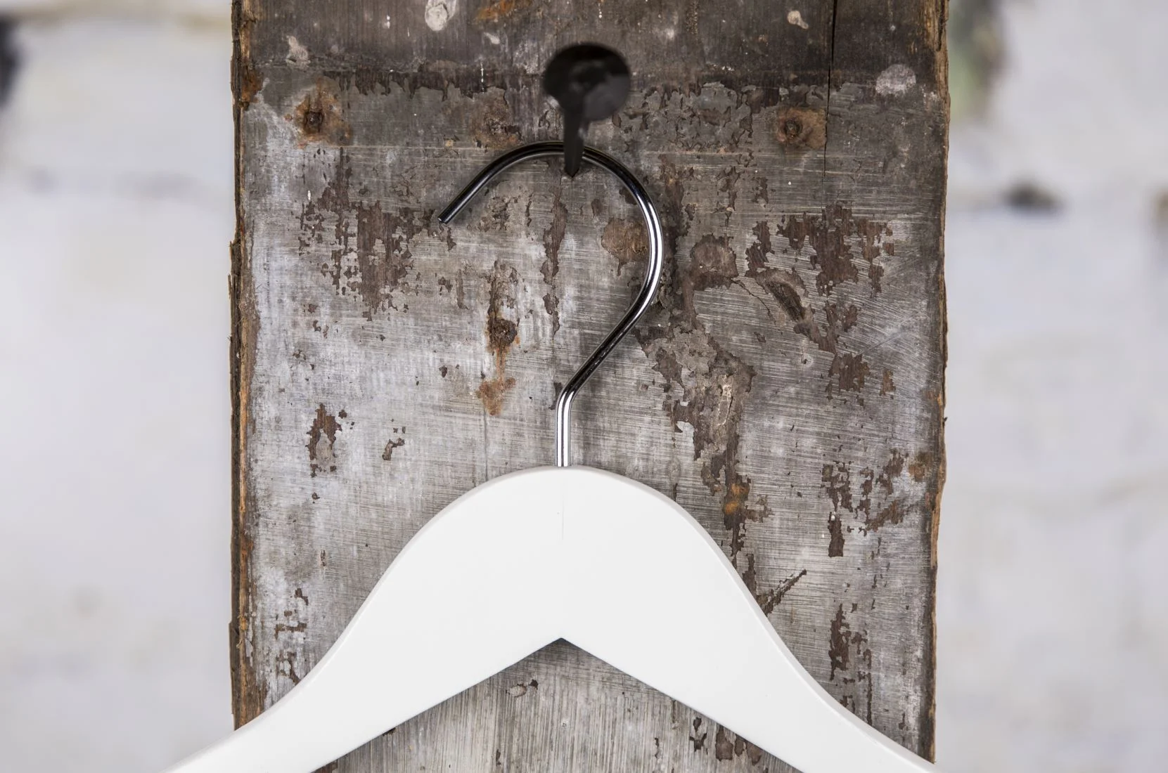 Weißer Kleiderbügel mit breiten Shouldertern, aufgehangen an rustikaler Wand – Schlichtes, elegantes Design für die gesamte Kollektion.