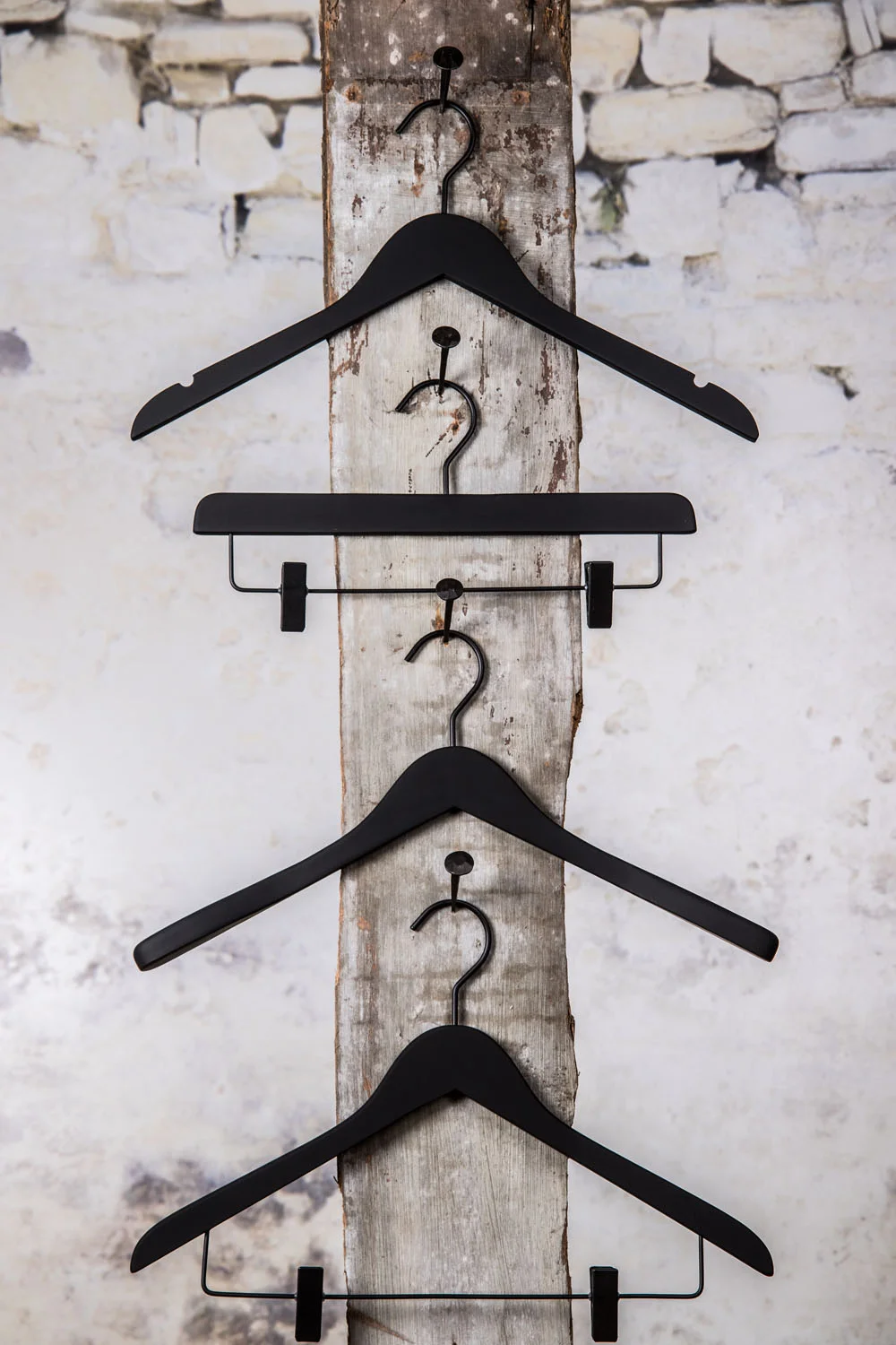 Drei schwarze Kleiderbügel mit einem mittleren Clip-Kleiderbügel, vertikal aufgehängt – komplette Präsentation für Ober- und Unterteile.