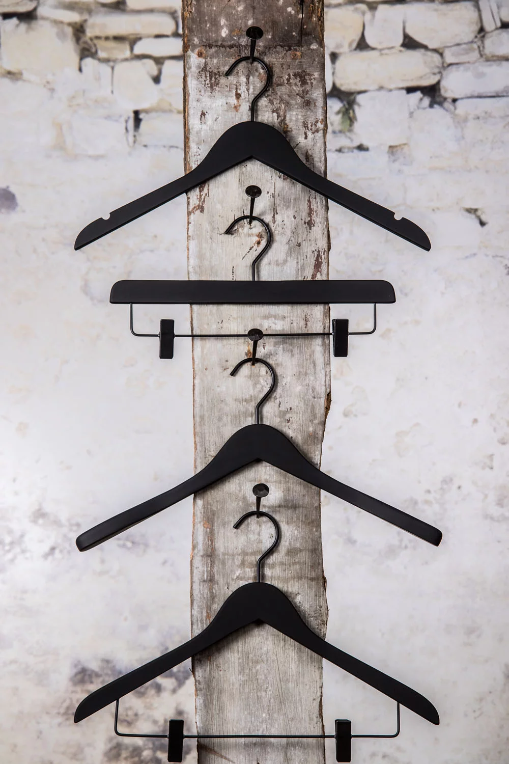Drei schwarze Bügel mit mittlerem Hosenbügel, vertikal präsentiert – Einheitliches, elegantes Set.
