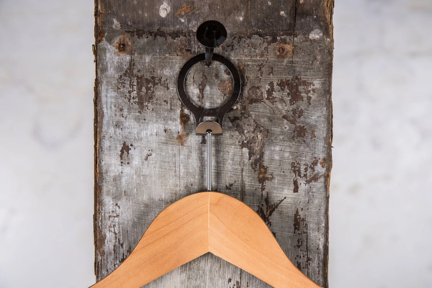 Kleiderbügel aus Naturholz mit runder Form, aufgehängt an einem Eisenring – Harmonisches Design für traditionelle Präsentation.