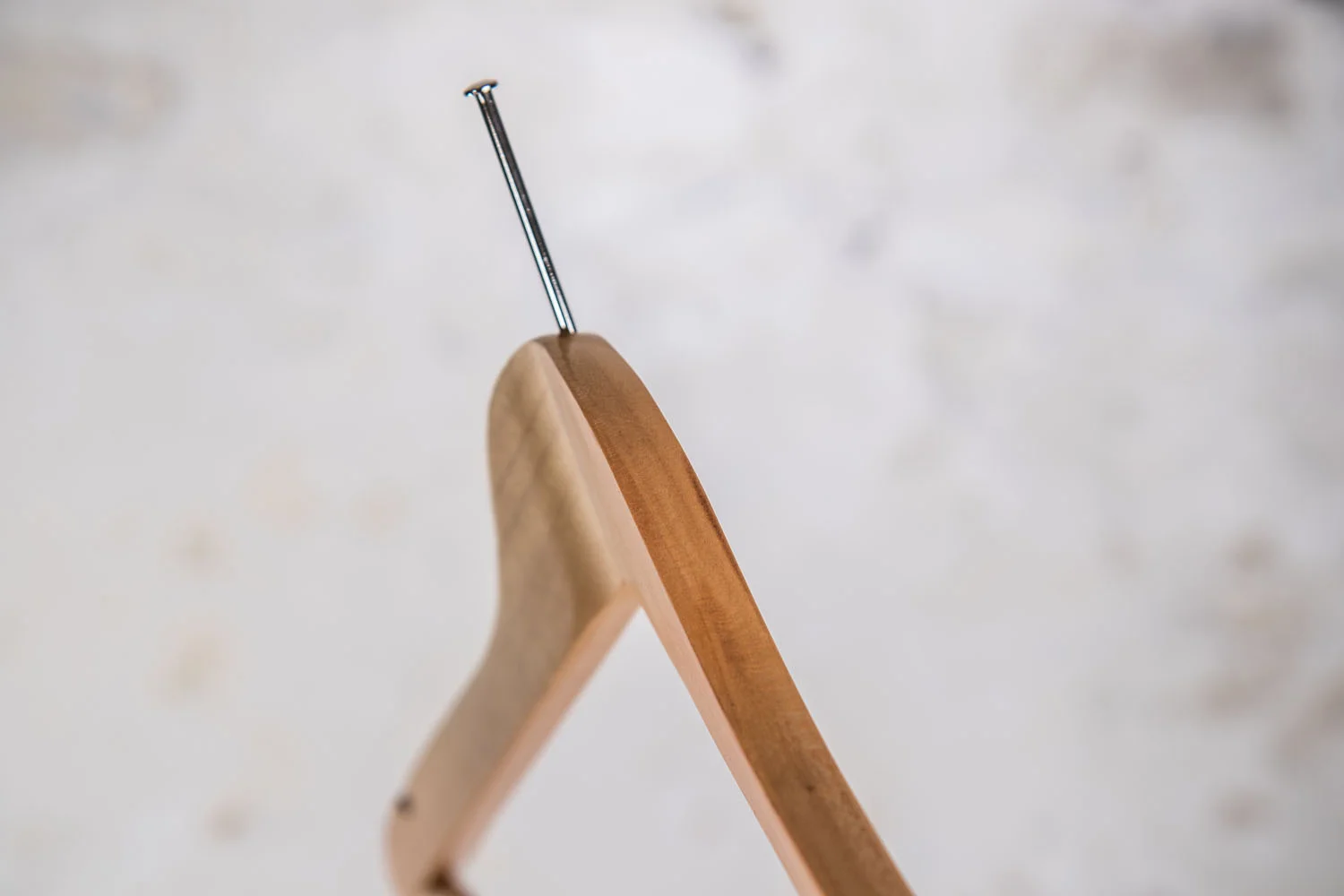 Seitenansicht eines naturfarbenen Holzbügels mit Haken - Solide Handwerkskunst im Detail.