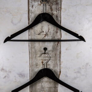 Zwei schwarze Kleiderbügel, vertikal montiert, an weißer Wand – Elegante Präsentation für moderne Kollektionen.