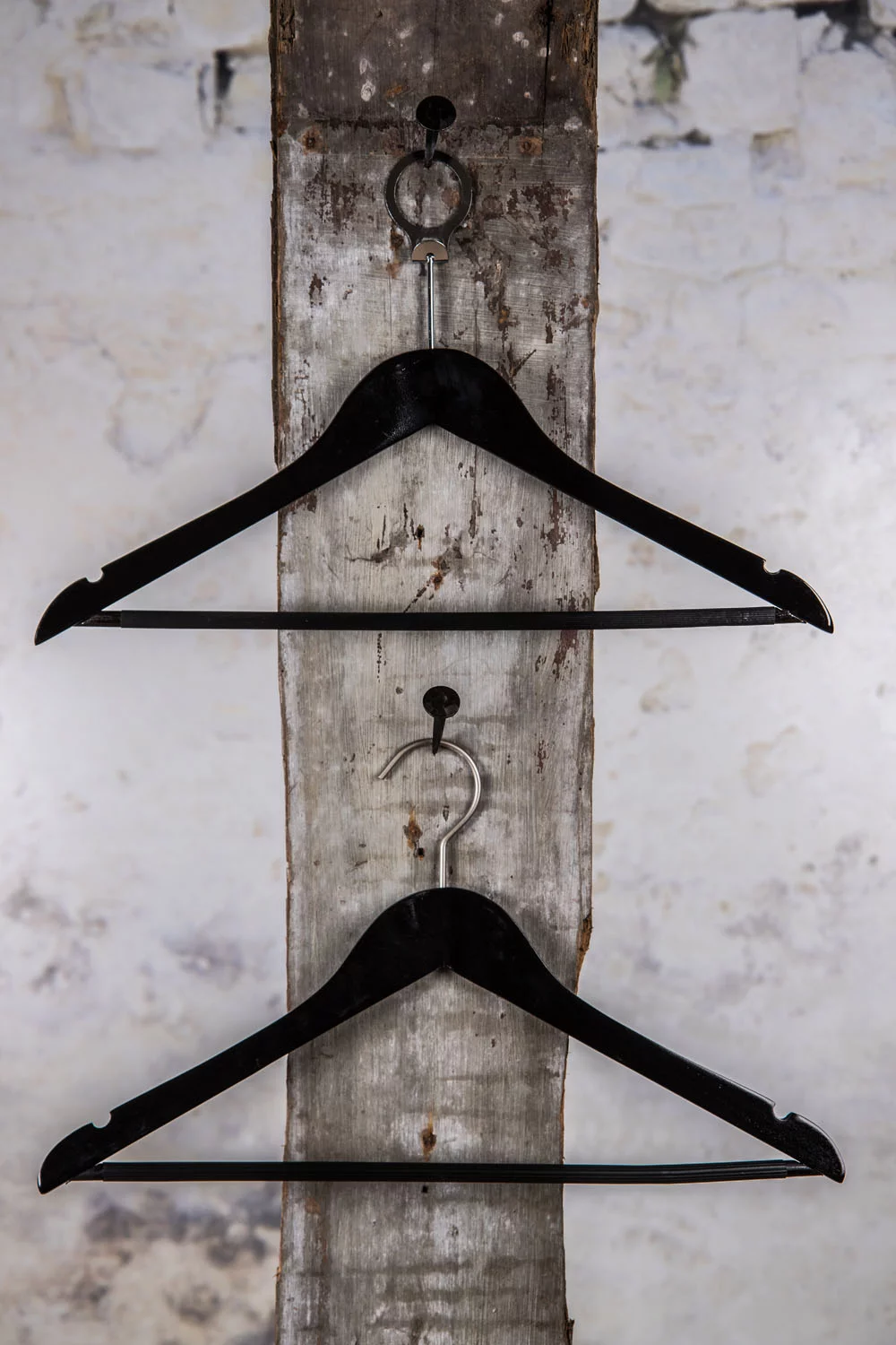 Two black clothes hangers, vertically mounted, on a white wall – Elegant presentation of the modern collection.