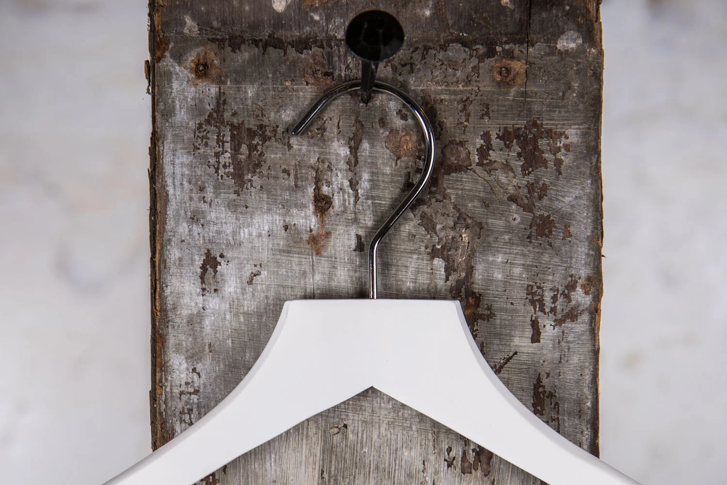 White hanger with broad shoulders, hung on rustic wall - Stable and professional presentation of structured outerwear in store and showroom.