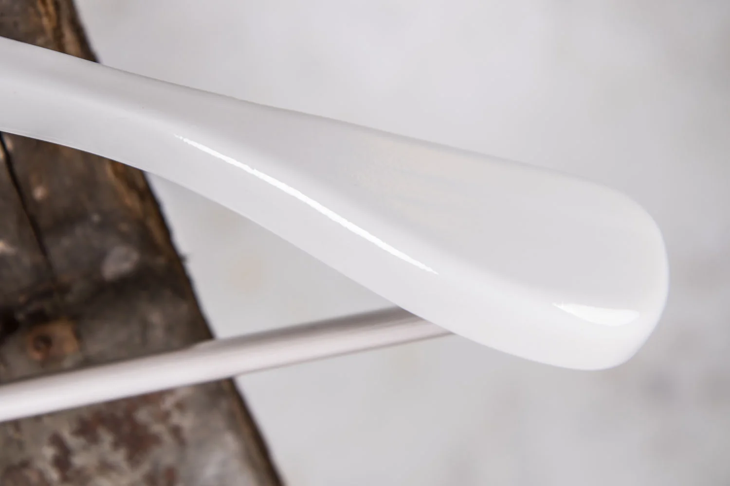 Detail of curved shoulder on white coat hanger – Elegant shape that supports and protects delicate textiles in stores and showrooms.