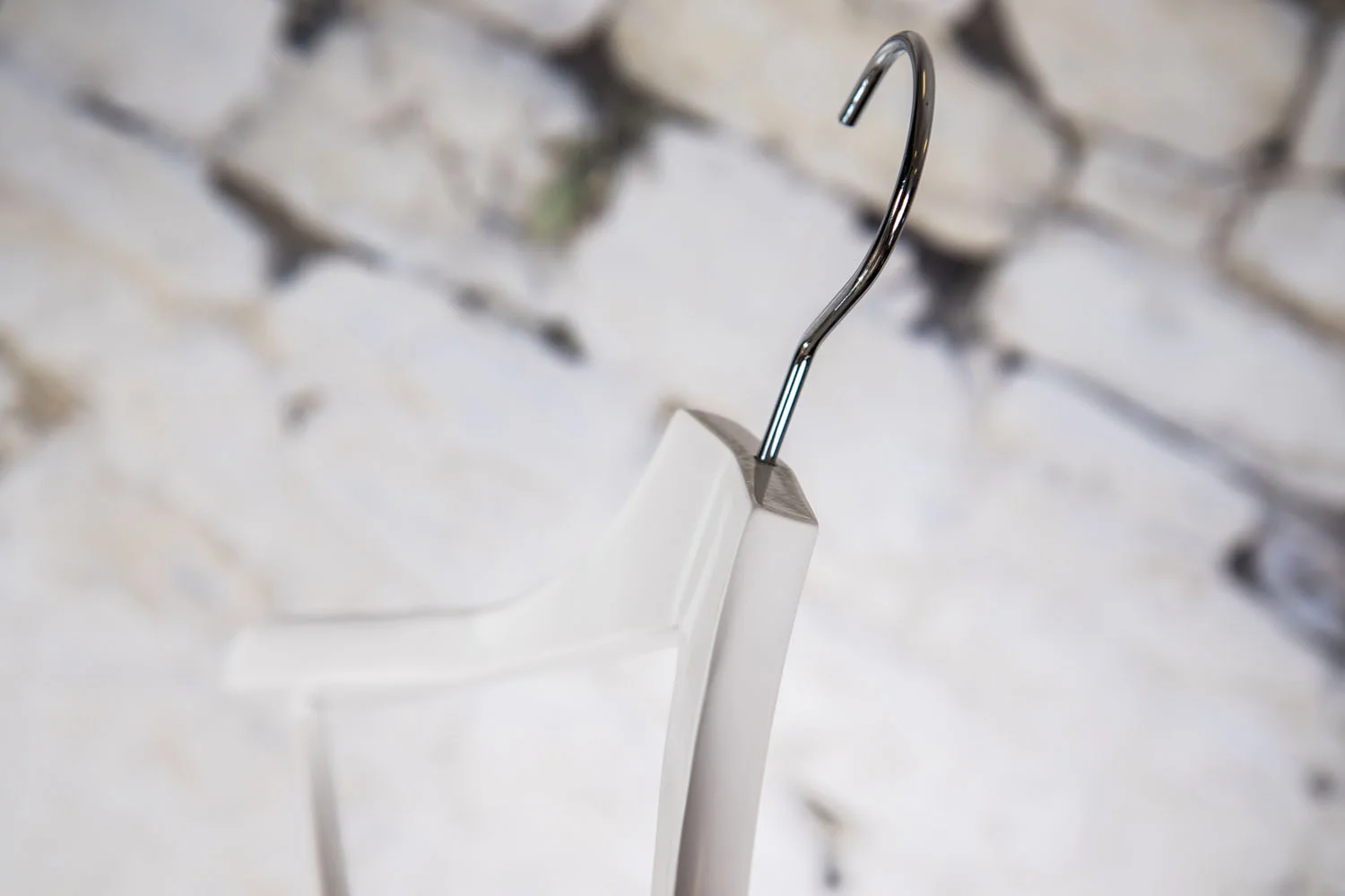 Detail of white hanger with metal hook seen from above - Clear transition between materials and stable suspension for professional use in stores and showrooms.