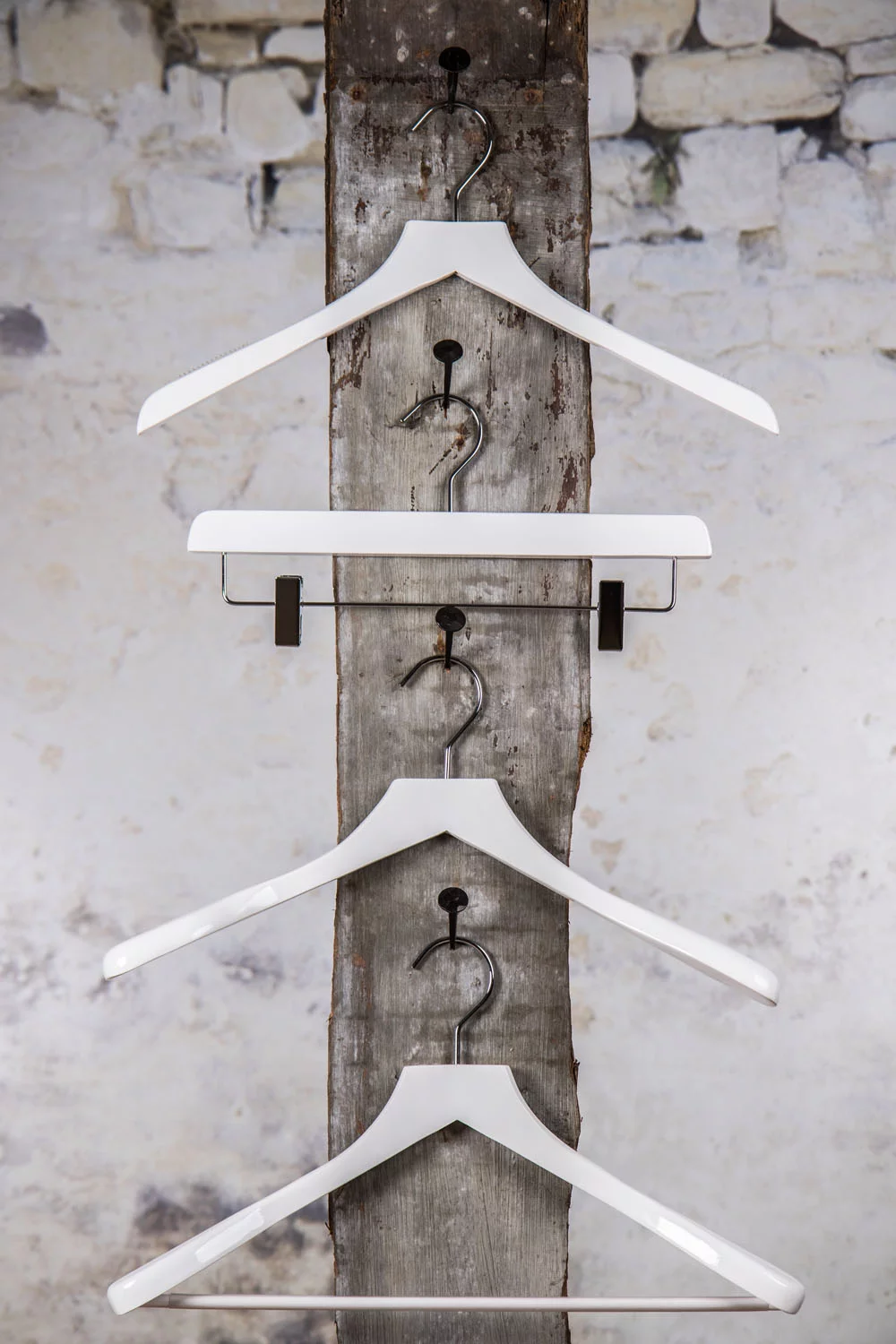 Three white hangers presented vertically with a middle clamp hanger – Uniform and stylish solution for professional presentation in stores and showrooms.