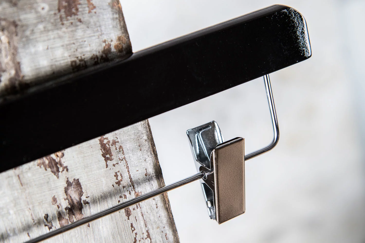 Detailansicht eines schwarzen Hochglanz-Hosenbügels mit silbernem Clip – Stilvolles Zusammenspiel aus Glanz und Metall.