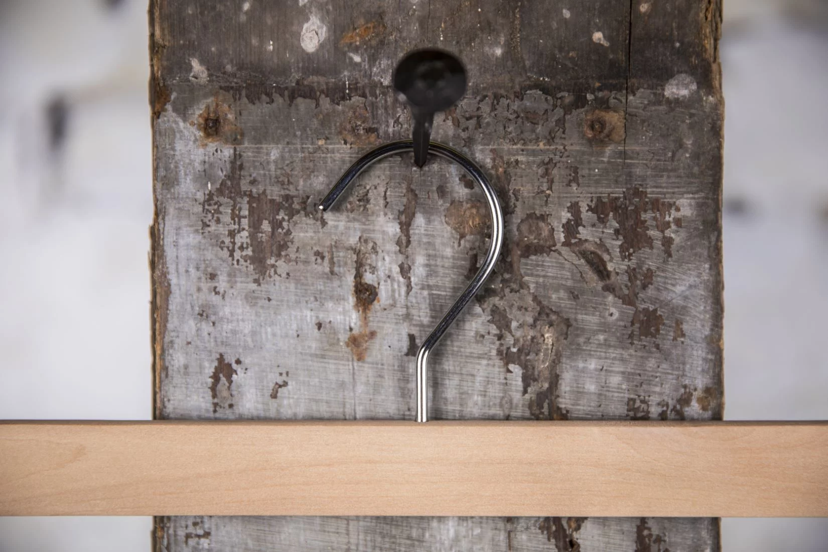 Hosenbügel aus Naturholz mit schwarzem Metallstab und Haken, zum Aufhängen an einer rustikalen Wand – Klassischer Stil für professionelle Präsentationen.