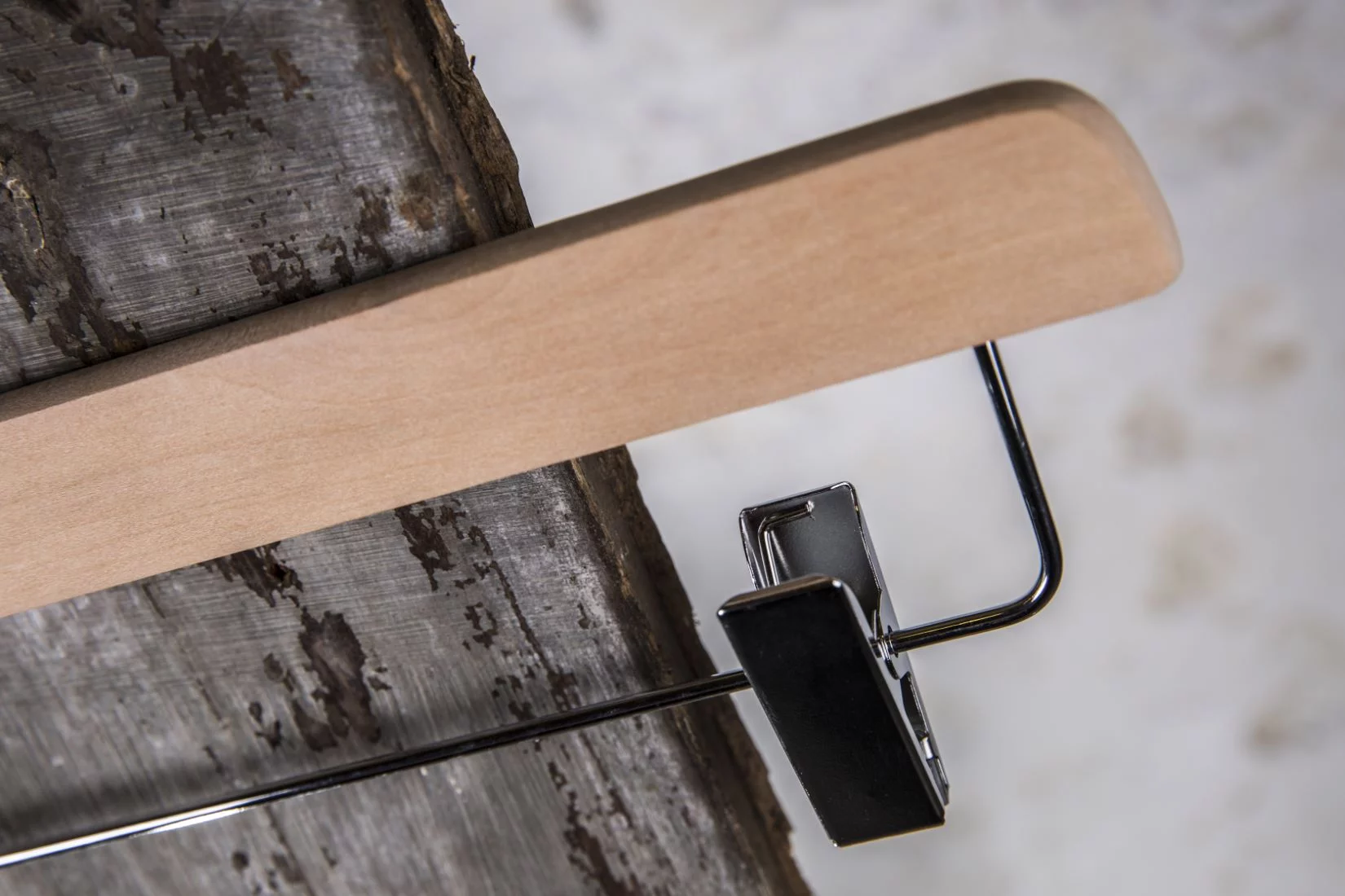 Detailansicht eines naturfarbenen Hosenbügels mit schwarzem Clip – Fokus auf Clipmechanik und Materialkontrast.