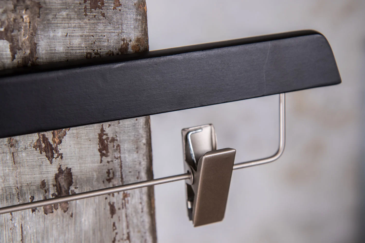 Detailaufnahme eines silbernen Clips an schwarzem Bügel – Materialkontrast zwischen Holz und Metall.