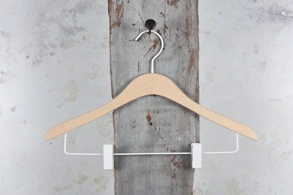 Hosenbügel aus Naturholz mit weißer Metallstange und Clips – funktionaler Kleiderbügel mit heller und moderner Optik.