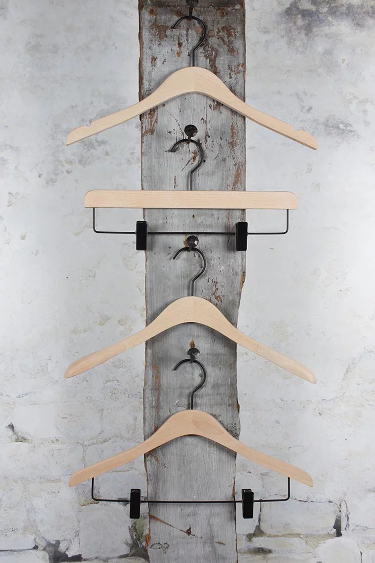 Vier naturfarbene Holzkonsolen vertikal an einer Wandhalterung aufgehängt – platzsparende, stilvolle Präsentation für Ausstellungsräume.