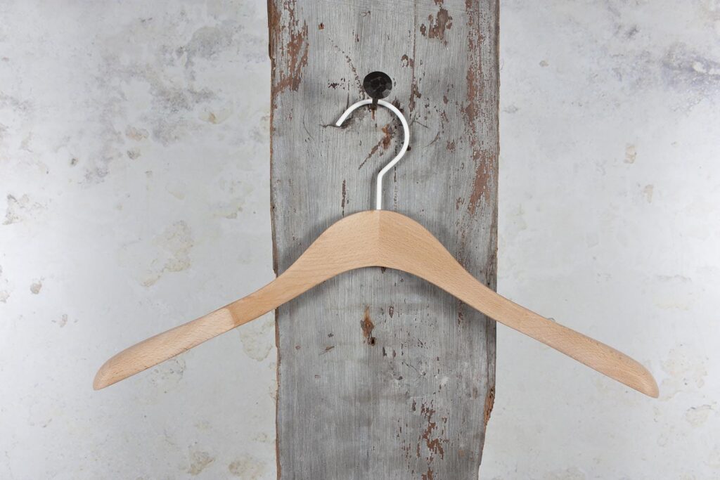 Natural colored wooden hanger on wall hanging – Slichter Kleiderbügel for versatile use.
