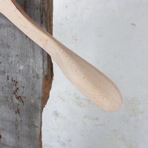 Detail der geschwungenen Schulter eines Holzbügels auf rustikaler Wand – Elegantes Design für exklusive Kollektionen.