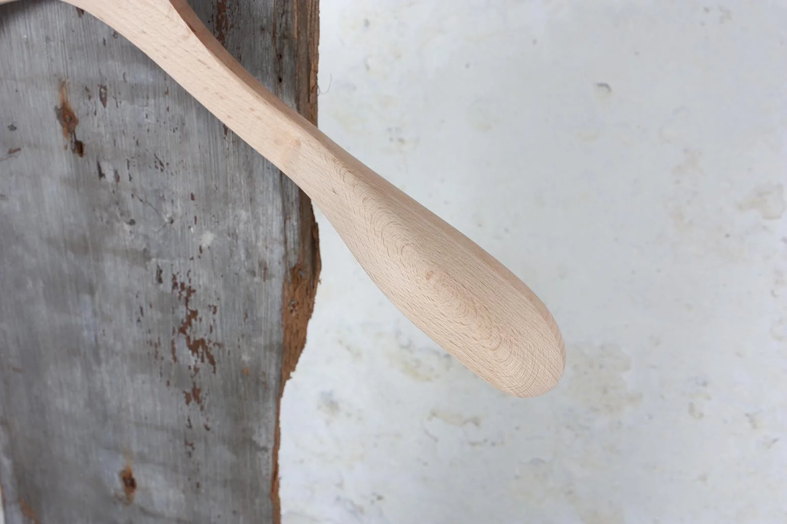 Detail der geschungenen Schulter eines Holzbügels auf rusticaler Wand – Elegante Design für exklusive Kollektionen.