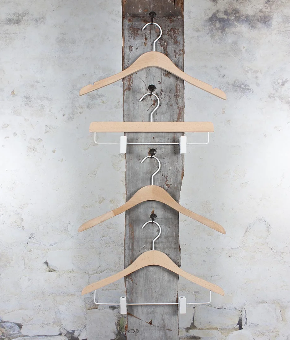 Fünf Holzbügel vertikal montiert an einer weißen Wandhalterung – Platzsparendes Aufbewahrungssystem mit natürlichem Look.