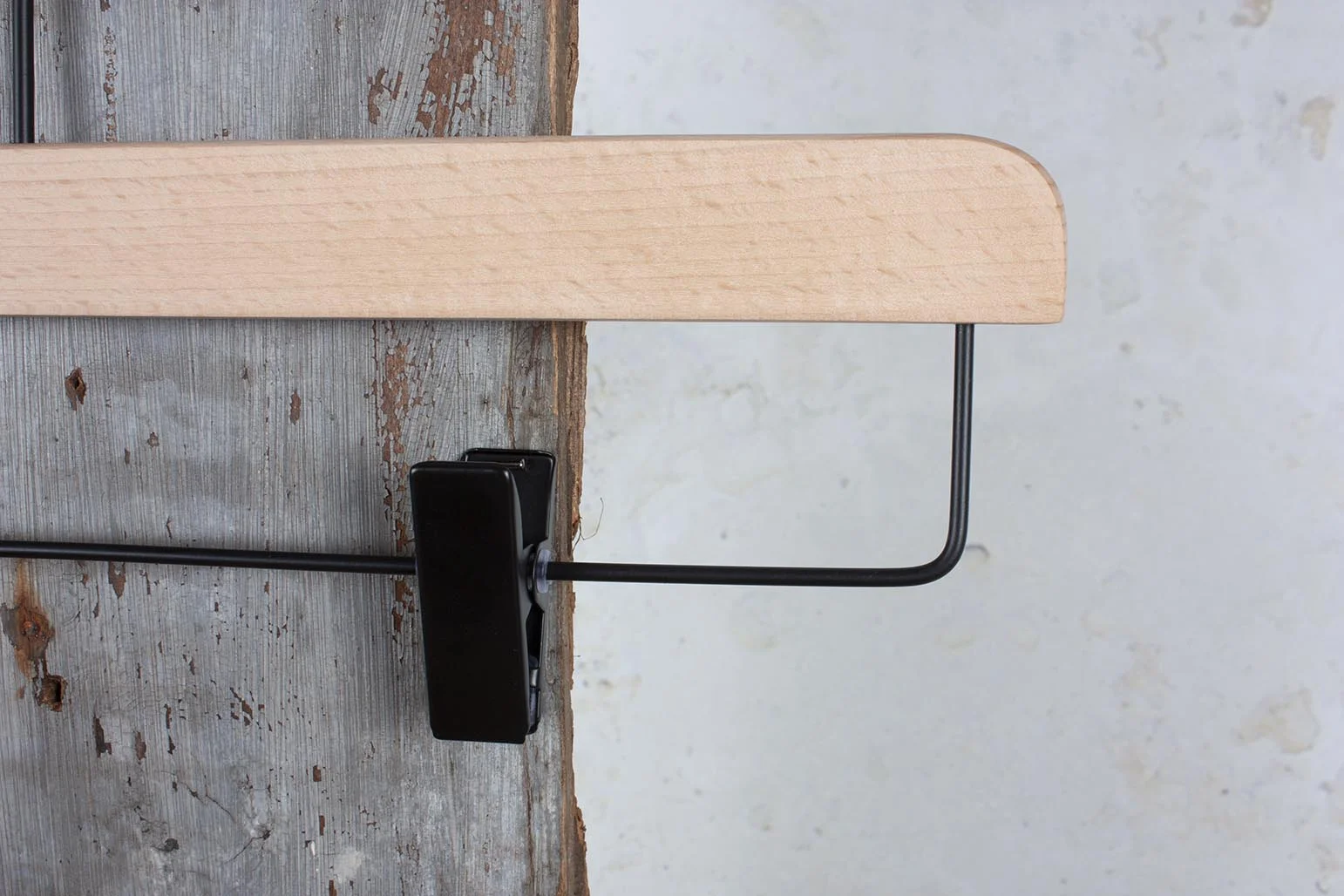 Detail eines naturfarbenen Hosenbügels mit schwarzem Clip – Nahaufnahme von Material und Funktion.