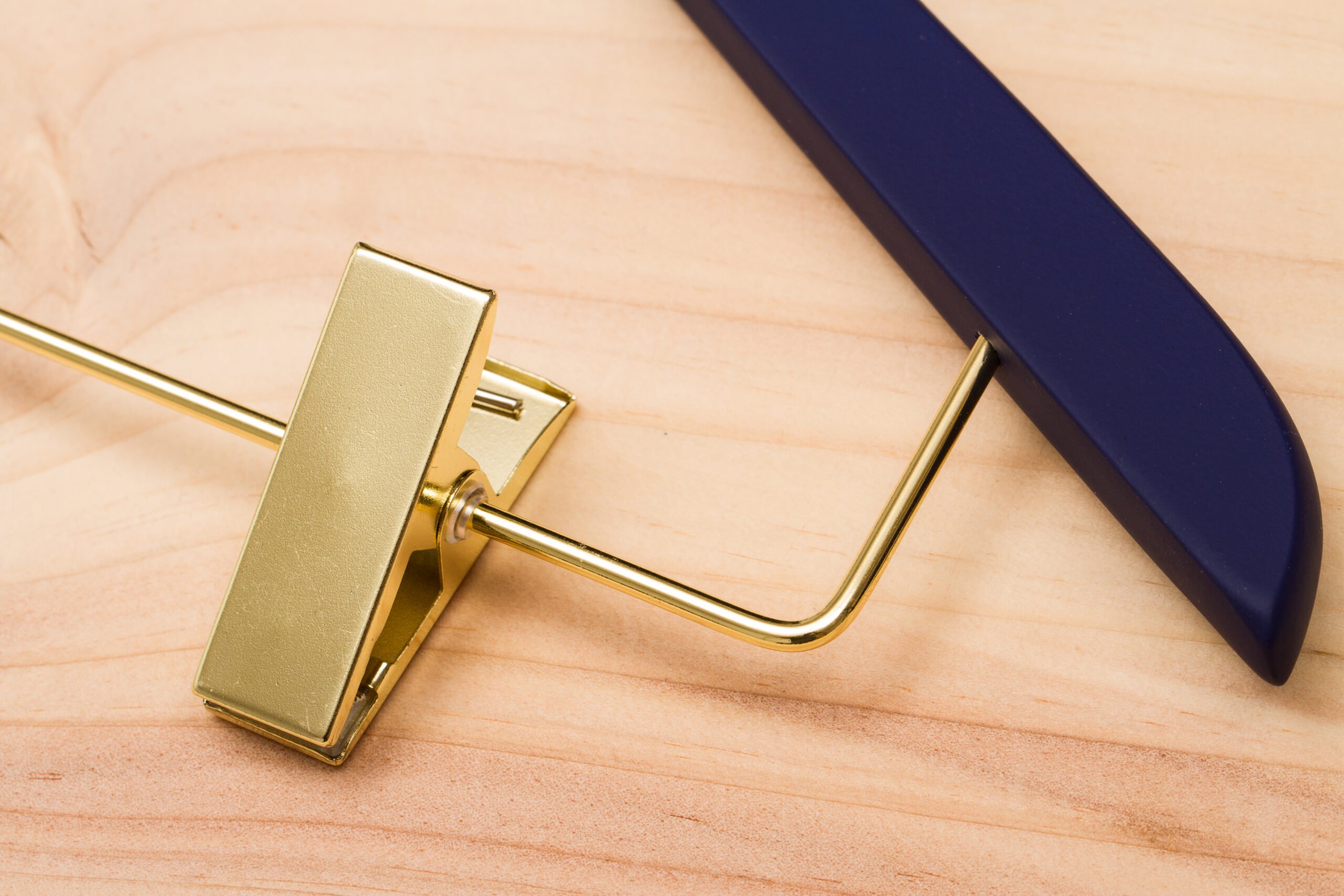 Goldfarbener Metallhaken für Kleiderbügel mit elegantem Erscheinungsbild von vorne vor einem einfarbigen Hintergrund