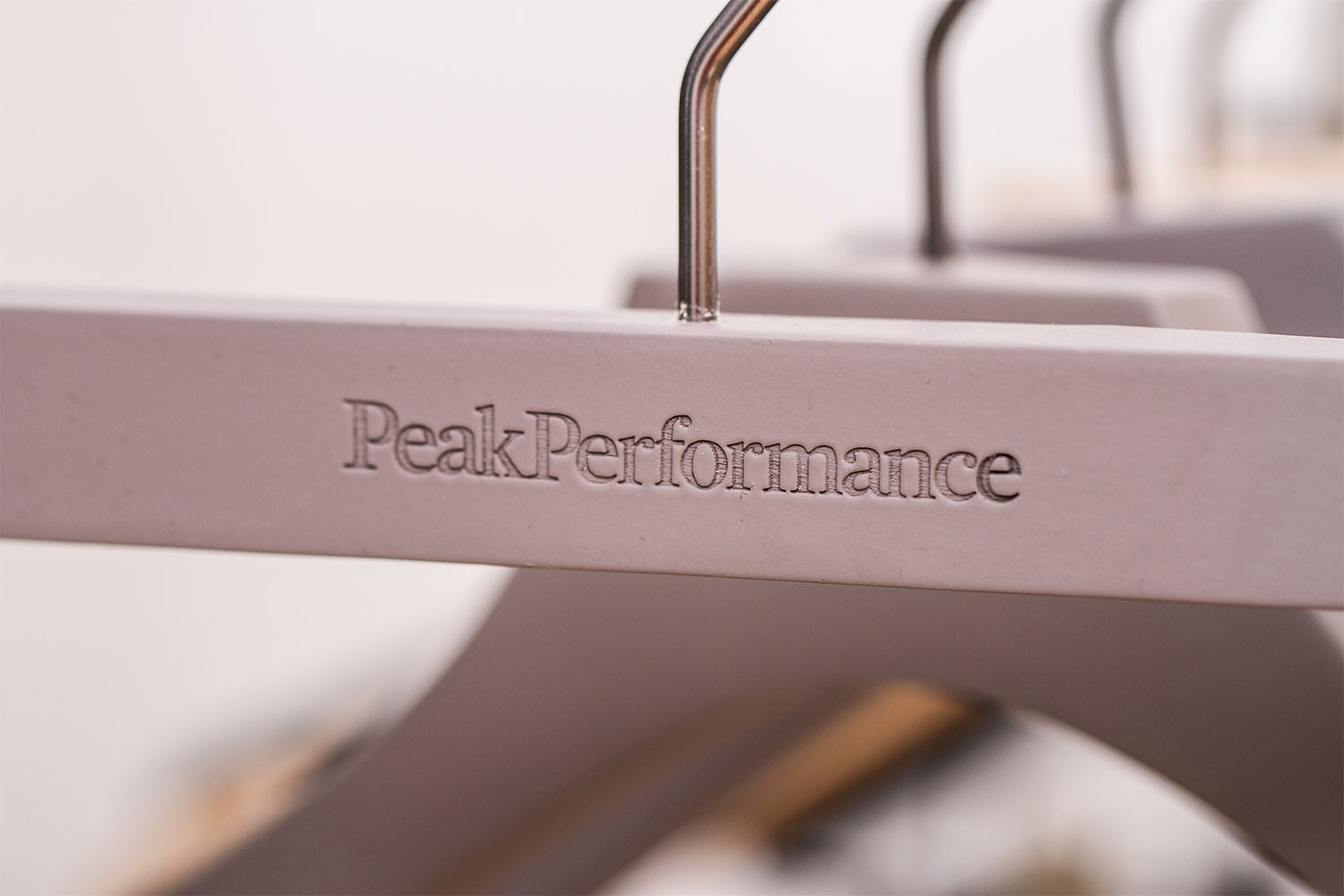 Blauer Kleiderbügel mit "PeakPerformance"-Logo für eine stilvolle Präsentation.