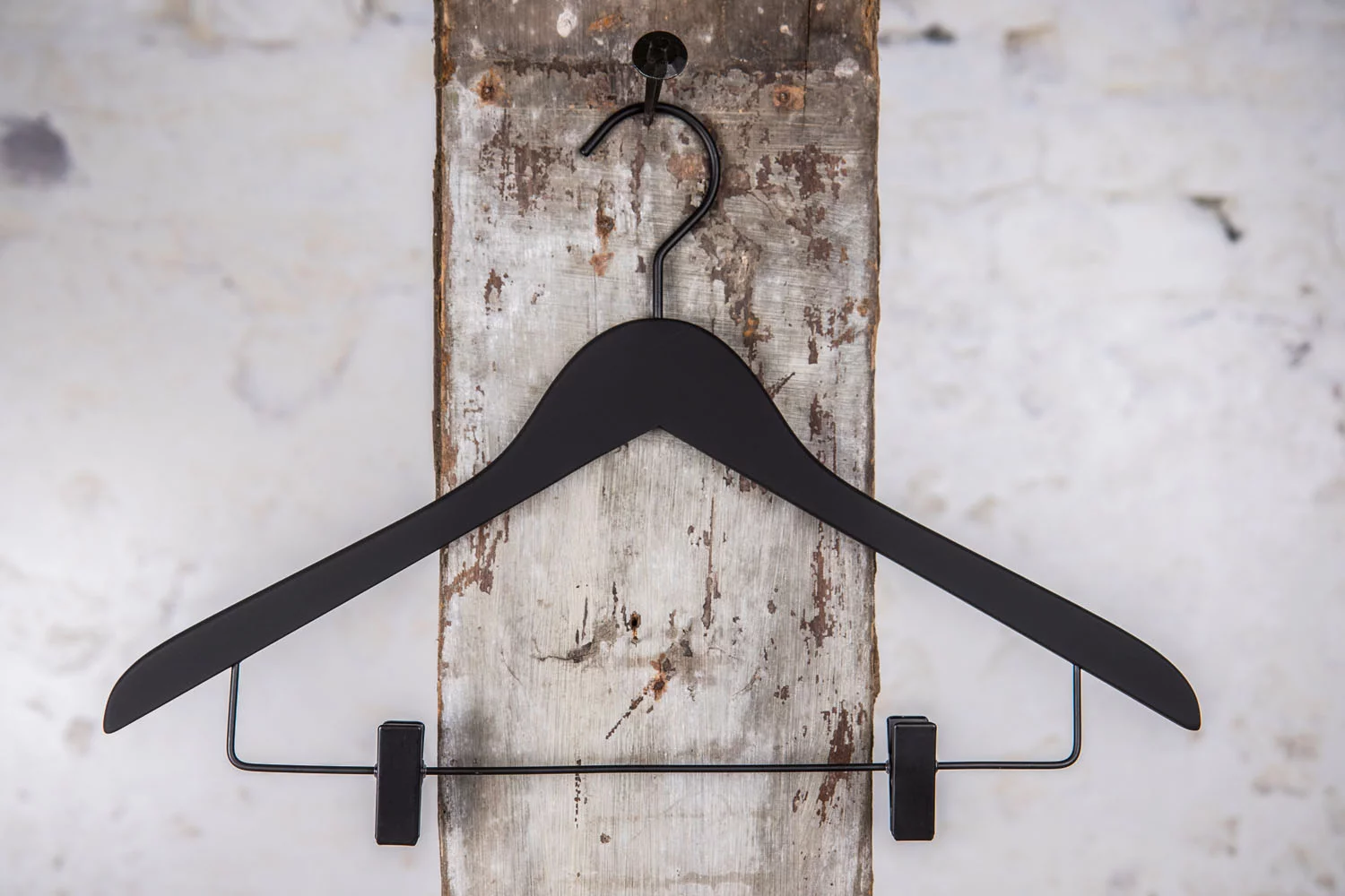 Sort bøjle med klemmer til bukser og nederdele, anvendt til professionel ophængning af tøj i butik og showroom