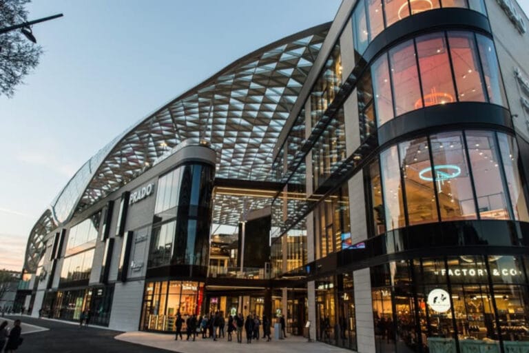 Moderne shoppingcenter med butiksfacader og glasarkitektur, der illustrerer professionelle retail- og shop-in-shop løsninger