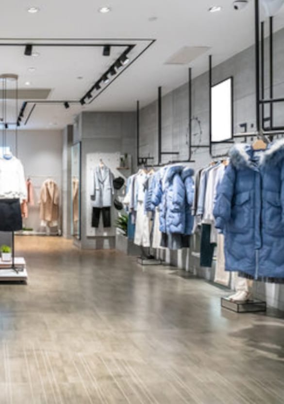 Modebutik med professionel tøjpræsentation på bøjler, der illustrerer retailmiljø og butiksindretning til B2B